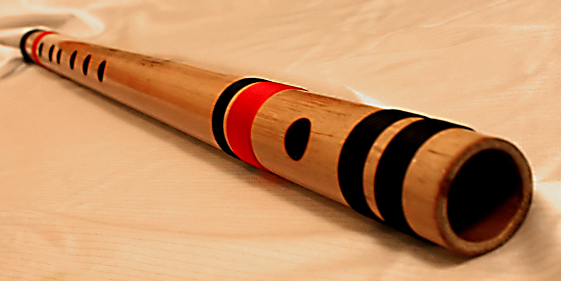 Close-up of a concert-length bamboo bansuri showing the blowing hole and finger holes