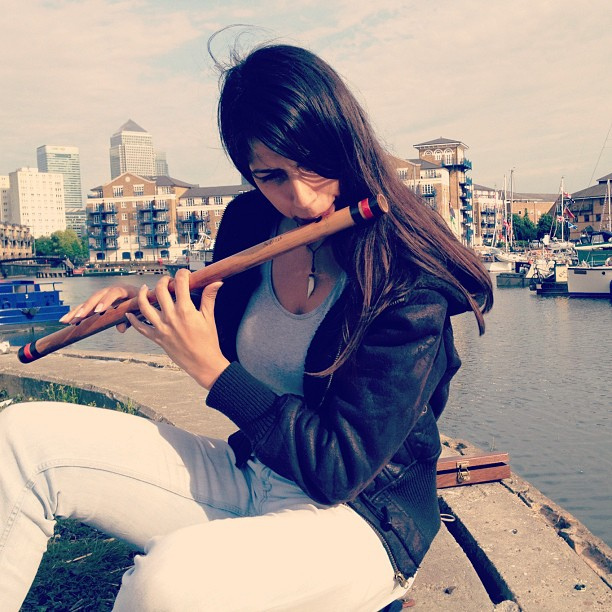 Both hands on a bansuri: finger pads covering the holes, thumbs supporting from underneath