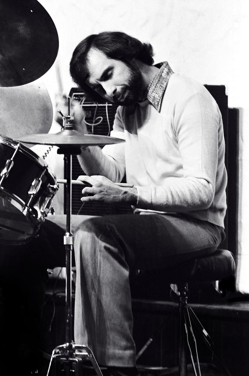 Joe LaBarbera seated side-on at a drum kit. He sits on the front of a round throne, back upright, thighs sloping a little down toward the floor.